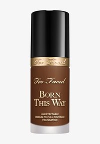 Too Faced Born This Way Foundation in einer braunen Flasche mit glänzend schwarzem Verschluss. Der Text auf der Flasche ist goldfarben und gibt den Abdeckungsgrad an.