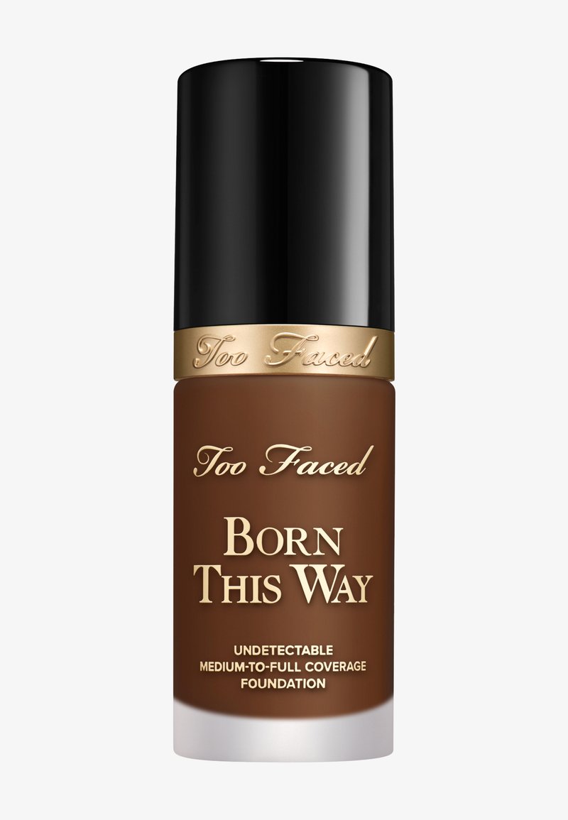 Too Faced Born This Way Foundation in einer braunen Flasche mit glänzend schwarzem Verschluss. Der Text auf der Flasche ist goldfarben und gibt den Abdeckungsgrad an.