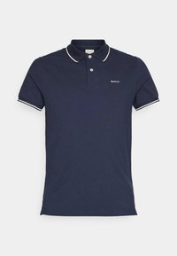 Kraljevsko plava polo majica s kratkim rukavima, kontrastnim bijelim obrubom oko ovratnika i malim izvezenim logotipom na prsima. Izrađena od pamučnog materijala.