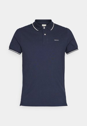Polo blu navy con maniche corte, rifiniture bianche a contrasto sul colletto e un piccolo logo ricamato sul petto. Realizzato in materiale di cotone.