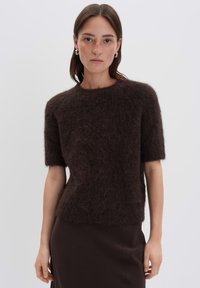 Pull en mohair mélangé marron à manches courtes avec une finition texturée et duveteuse et un col rond, associé à une jupe ajustée unie marron.