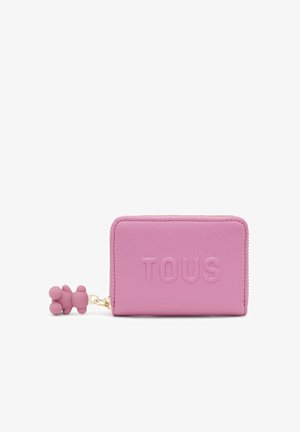 Portafoglio in pelle rosa con logo "TOUS" in rilievo, finitura texturizzata, chiusura con cerniera e ciondolo a forma di orsetto attaccato.