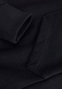 Tecido de sweatshirt preto mostrando um punho dobrado com uma textura fiada e costura limpa ao longo das bordas, enfatizando a simplicidade e a funcionalidade.