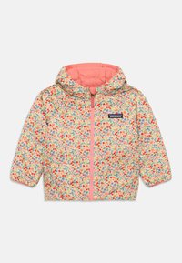 Veste à capuche à motifs floraux en jaune clair avec des accents roses, dotée d'une fermeture éclair à l'avant et d'une étiquette logo Patagonia.