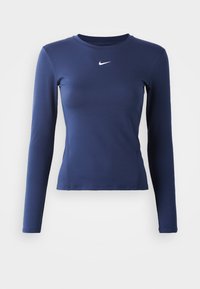 Majica dugih rukava za sport u mornarsko plavoj boji, izrađena od glatkog materijala s uskim krojem. Ima mali bijeli Nike logo na prsima.