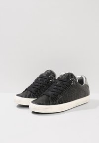 Scarpe da ginnastica nere con un design a stampa serpente testurizzata, punta rotonda, lacci neri, accenti argentati sul tallone e suole in gomma bianca.