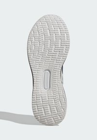 Suela de zapato de goma blanca con un patrón texturizado, que presenta surcos y relieve para mayor tracción y un acento circular en el área del mediopié.