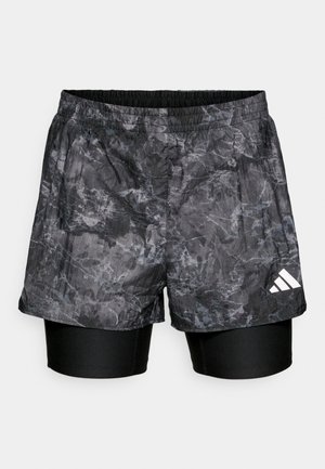Schwarz-grau gemusterte Sportshorts, die über enganliegende schwarze Unterhosen getragen werden, mit elastischem Bund und weißem Markenlogo.
