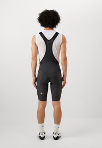 Cuissard de vélo noir avec un design ajusté, une selle rembourrée et des bretelles en mesh. Présente un petit logo rouge sur la cuisse gauche.