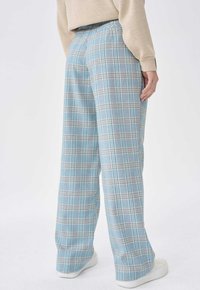 Lichtblauwe geruite broek met een ontspannen pasvorm, voorzien van een elastische tailleband en witte schoenen, met een zachte stoffen textuur.