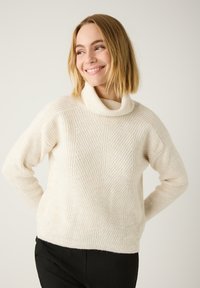 Cremefarbenes, geripptes Strickpullover mit hohem, umgeschlagenem Kragen und diagonalen Mustern. Weicher Stoff, lässige Passform und lange Ärmel.