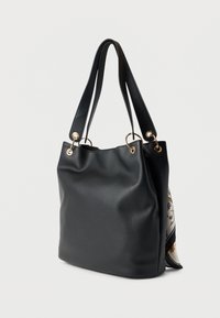Black textured leather tote bag with double shoulder straps and gold rings, featuring a partially visible floral scarf on the side.