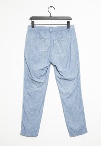 Pantaloni in chambray blu chiaro con vestibilità rilassata, dotati di due tasche posteriori e orli risvoltati, esposti su una gruccia nera.