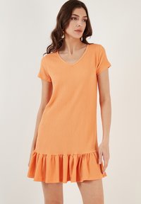 Short orange dress with a v-neck and short sleeves. Textured fabric features a flounced hemline for added detail.