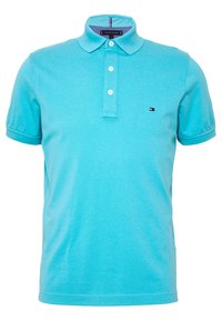 Ljusblå pikétröja i bomull med treknäppning, korta ärmar och en liten logotyp på bröstet. Slät textur.