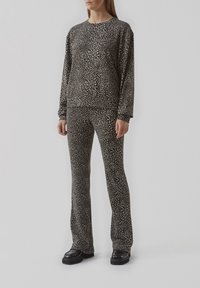 Zwart en beige gemarmerde lounge-kledingset, bestaande uit een langemouwen top en uitlopende broek, gemaakt van zachte stof met een gladde textuur.