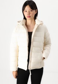 Cremefarbene Steppjacke mit Kapuze, Reißverschluss und seitlichen Taschen. Merkmale sind das horizontale Steppmuster und die gerippten Bündchen für zusätzliche Wärme.