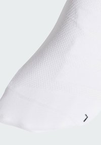 Calzino bianco alla caviglia con una maglia testurizzata e traspirante, che presenta un logo nero sulla caviglia. Finitura liscia e vestibilità aderente per il massimo comfort.