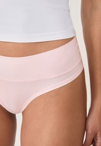 Mutande moderne rosa chiaro con una texture liscia e un ampio elastico in vita. Presenta un design senza cuciture e una minimalistica cucitura per il massimo comfort.