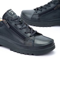 Baskets en cuir noir avec une semelle en caoutchouc texturé, design à lacets, fermeture éclair et une étiquette logo sur la languette. Fini lisse et construction solide.