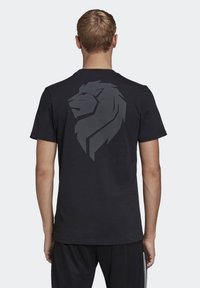 Černé tričko s krátkým rukávem vyrobené z bavlny, s velkým šedým grafiky lva na zádech. Jednoduchý design s kulatým výstřihem a volným střihem.