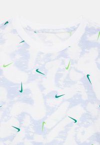 Fehér póló, lágy textúrával és kék absztrakt mintával, melyben apró zöld Nike logók találhatók a design egészében.