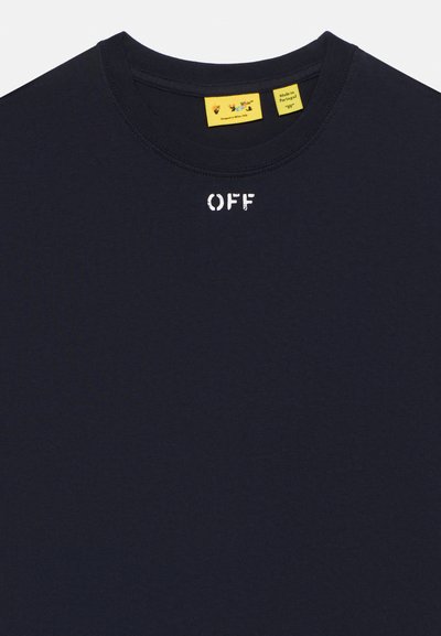 Σκούρο μπλε μπλούζα με στρογγυλή λαιμόκοψη, φθαρμένο λευκό κείμενο "OFF" στο κέντρο κάτω από το λαιμόκοψη και δύο κίτρινα ετικέτες μέσα στη λαιμόκοψη.