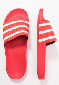 Röd slidesandal med en texturerad rem som har tre vita ränder. Slät syntetisk material, kurvad fotbädd för komfort.