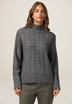 Maglione lavorato a maglia di un grigio scuro con colletto alto, caratterizzato da un motivo a treccia in rilievo e bottoni decorativi lungo la parte anteriore. Polsini e orlo a costine.