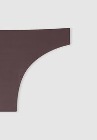 Primo piano di perizoma bikini senza cuciture di colore marrone scuro su sfondo grigio chiaro, che mette in mostra il lato e l'area dell'anca con un tessuto liscio.