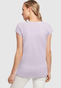 Light purple short-sleeve T-shirt with rolled cuffs, round neck, and a fitted design, made from a soft fabric with a smooth texture.