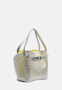 Zilveren geperforeerde tas met gele binnenkant. Heeft twee handvatten, een rechthoekige vorm en een metalen accent aan de voorkant.