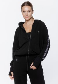 Czarna bluza z kapturem na zamek, wykonana z miękkiego materiału, z logo na piersi, długimi rękawami z akcentami logo i luźnym krojem.