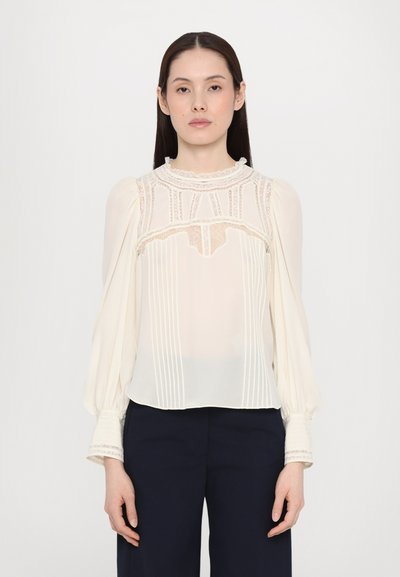 Blouse fluide crème avec des accents en dentelle, des détails plissés et de longues manches bouffantes. Tissu texturé avec un col rond et une finition délicate.