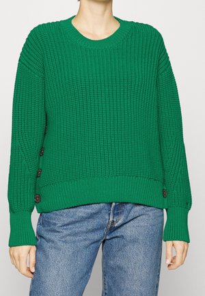 Maglione verde lavorato a maglia con texture a costine, scollo tondo e grandi bottoni sui lati. Vestibilità morbida con maniche lunghe e orlo corto.