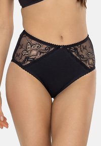 Pantaloni alti neri in vita con pannelli in pizzo a motivo floreale, bordi ondulati e un piccolo fiocco decorativo al centro frontale.