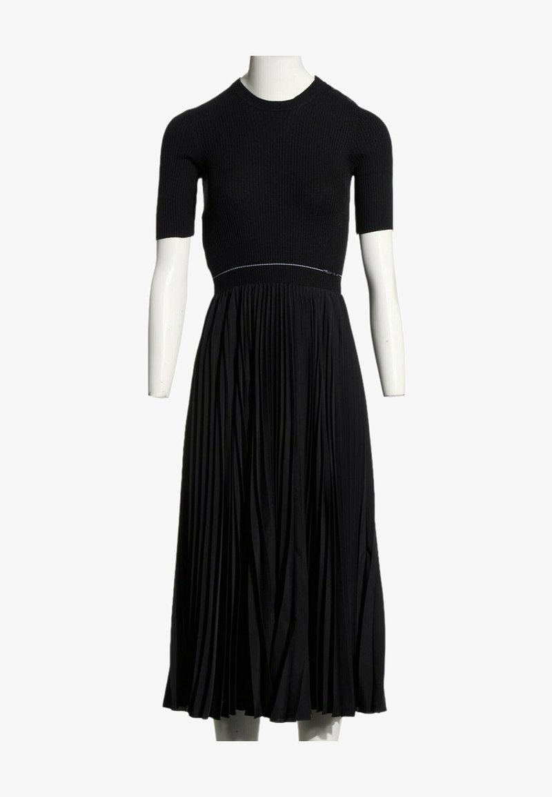 Robe midi noire avec haut ajusté à manches courtes côtelées et jupe fluide plissée, présentée sur un mannequin blanc sur fond blanc.