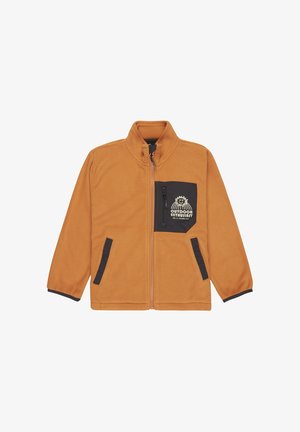 Chaqueta de forro polar en naranja con bolsillo con cremallera negra, con un diseño impreso. Un gorro de punto negro y unos vaqueros azules complementan las zapatillas negras.