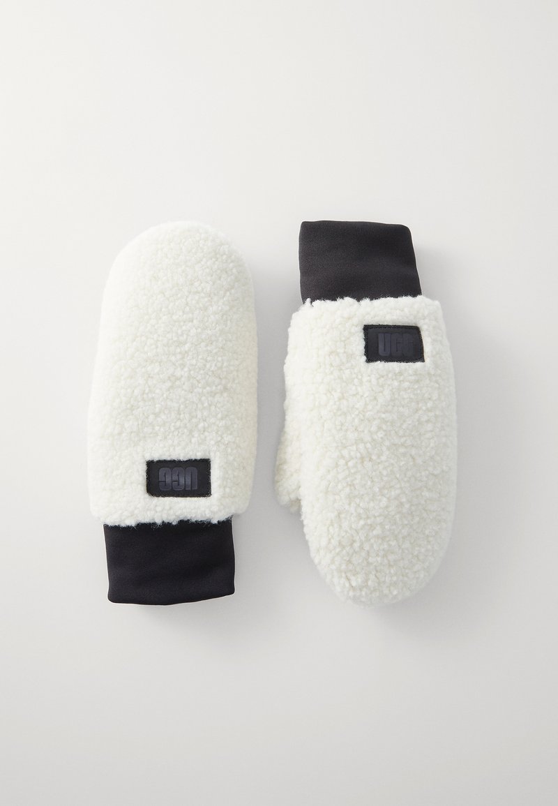 Moufles en polaire blanche avec des poignets en tissu noir, arborant un petit patch logo noir. Texture douce avec une forme arrondie, offrant chaleur et protection.