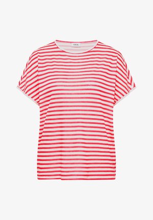 Frau lächelt, ist nach rechts gedreht, trägt ein kurzärmliges rotes und weißes horizontal gestreiftes Shirt und blaue Jeans, vor einem einfarbigen Hintergrund.