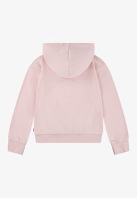 Rožinė striukė su minkšta tekstūra, turinti centrinį siūlą, prisegtą kapucę ir raštuotas rankogalius bei apatinę dalį. Jokie matomi grafikos dizainai ar akcentai.