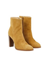 Paire de bottines en daim beige avec fermetures éclair latérales et talons carrés empilés, présentées sur un fond blanc.
