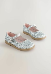 Scarpe Mary Jane argentate con glitter, dotate di una cintura e fibbia lucida, suola in gomma beige e rivestimento interno morbido rosa. Presentano un design a punta arrotondata.