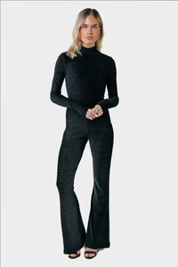 Set de două piese negre cu textura ribbed, format dintr-un top ajustat cu mânecă lungă și pantaloni evazați, confecționat dintr-un material elastic cu un finisaj texturat.