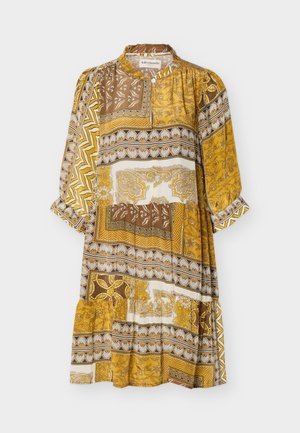 Robe midi à manches longues avec un motif patchwork dans des tons jaune moutarde, marron et crème, col montant, taille et poignets légèrement froncés.