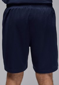 Pantalones cortos deportivos de color azul marino, confeccionados con un tejido ligero y transpirable con una textura perforada y una cinturilla elástica para mayor comodidad.