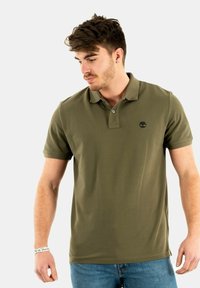 Polo shirt verde oliva scuro in maglina di cotone, con colletto, patta con due bottoni e un piccolo logo ricamato sul petto.