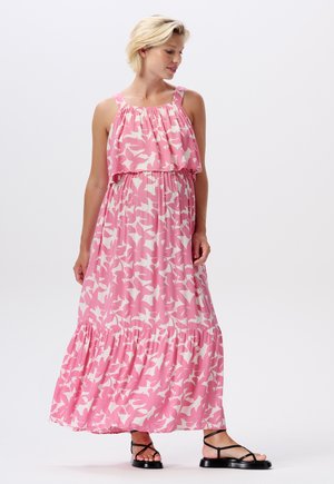 Maxikleid aus pinkem Stoff mit einem weißen Vogelmuster. Verfügt über ein geschichtetes Oberteil, einen elastischen Bund und einen rüschierten Saum. Sandalen mit Riemchen runden den Look ab.