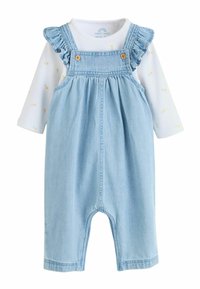 Ljusblå denimhänselbyxor med volangprydda axelband, träknappar och en vit långärmad tröja med pastellfärgade blommönster.