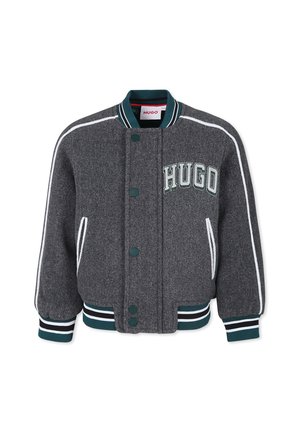 Veste universitaire grise avec poignets, col et bas rayés verts et blancs, ornée de passepoil blanc et du mot "HUGO" brodé sur la poitrine.